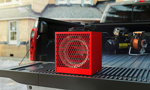 Chauffage électrique portatif rouge posé sur la caisse d’une camionnette sur un chantier