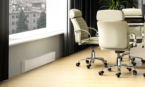 Plinthe électrique blanche installée sous une fenêtre dans un bureau moderne avec chaises sur roulettes, pour un chauffage efficace.