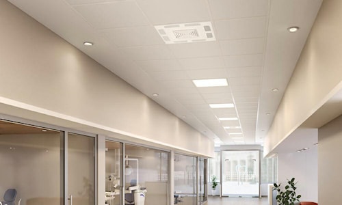 Plafond de bureau moderne équipé de luminaires DEL encastrés et d’une unité de ventilation, offrant un éclairage uniforme dans le corridor.