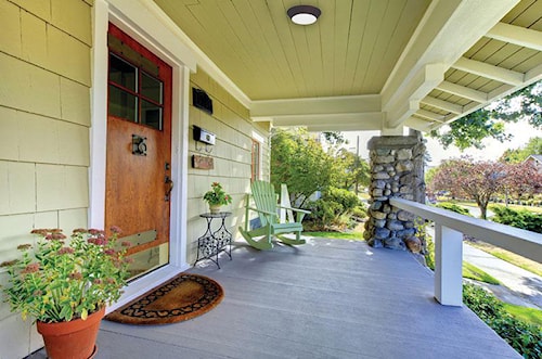 véranda de maison avec porte en bois, chaises Adirondack vertes et allée de jardin