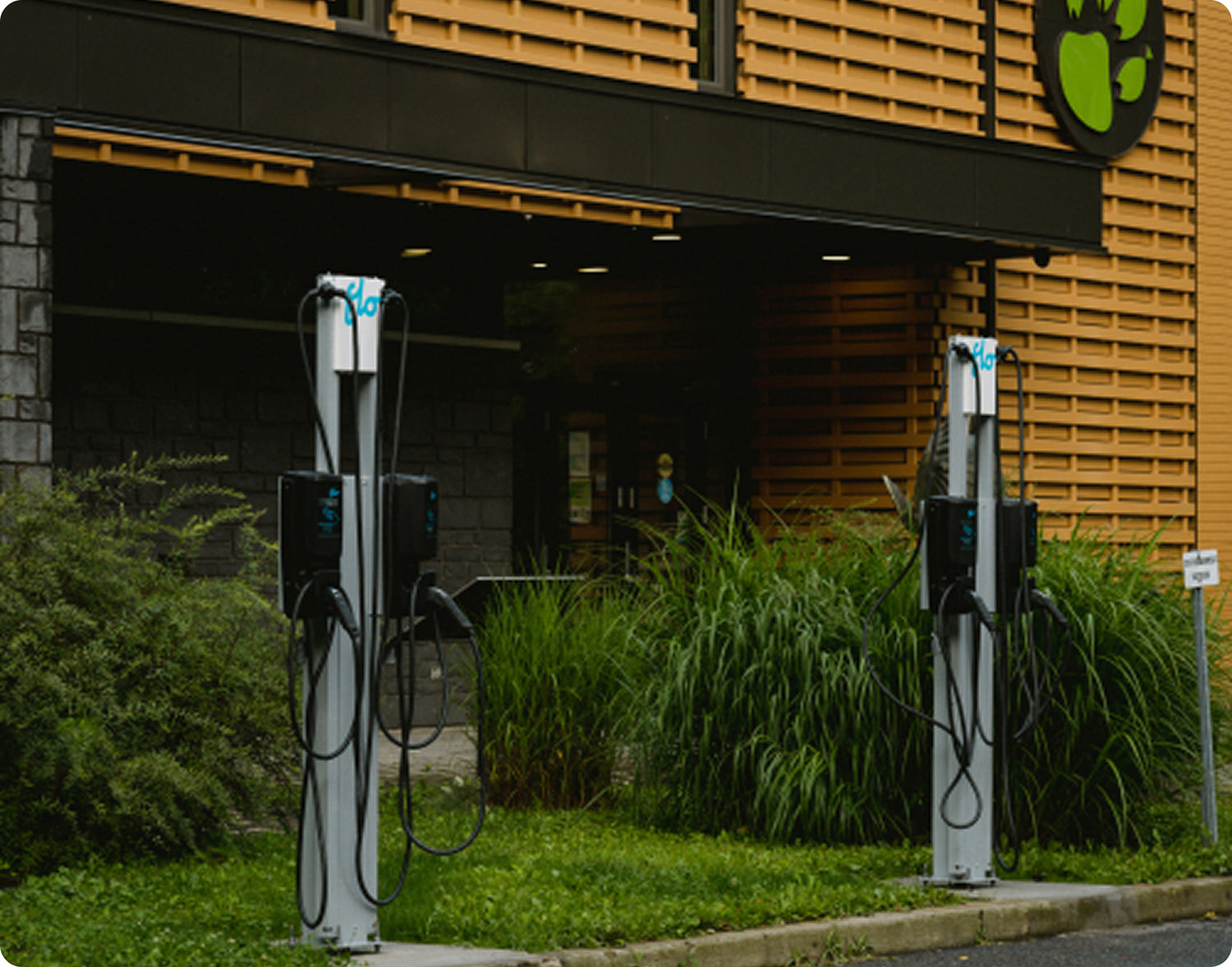 Deux bornes de recharge électriques installées devant un bâtiment commercial, offrant des stations de recharge publiques pour véhicules électriques.